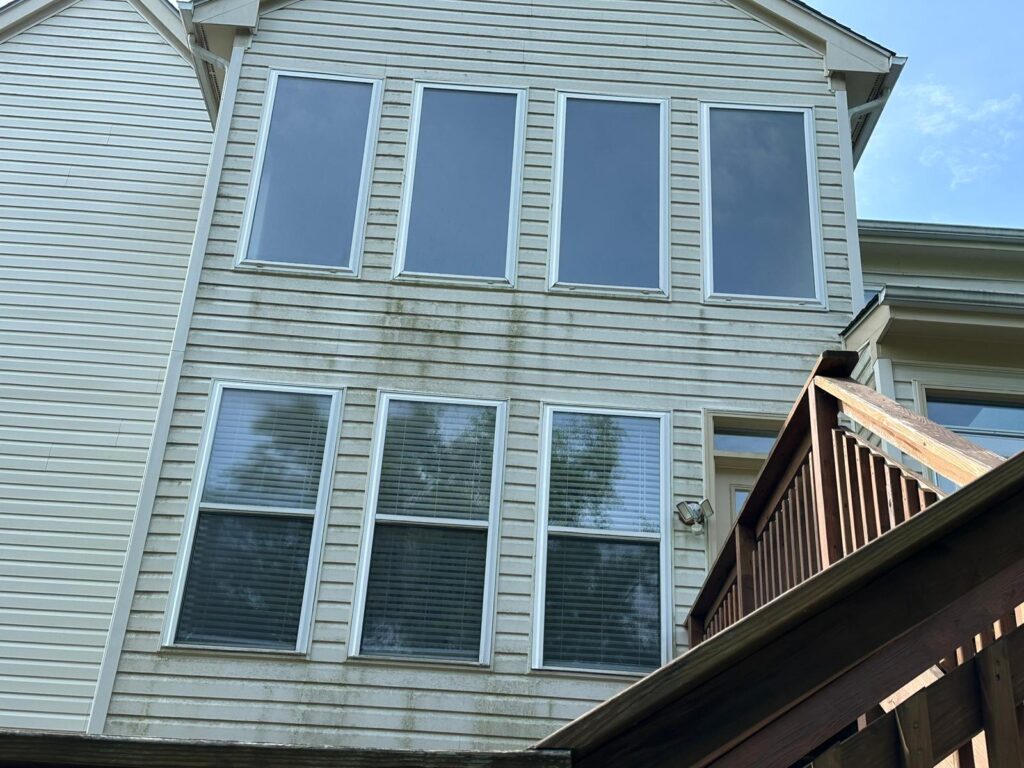 House soft wash in Fairfax, VA, with green-gray streaks still visible on siding below the windows.