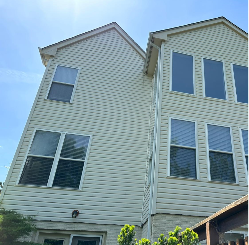 Before a house soft wash in Fairfax, VA, showing pale vinyl siding and windows on a multi-story home.